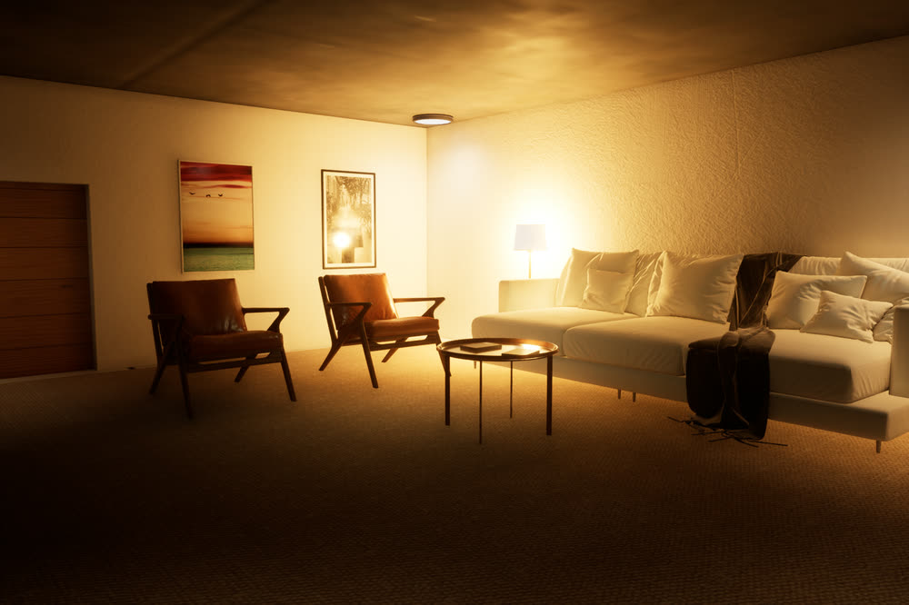 The living room in the evening, lit only by warm lamps: the white sofa, two leather armchairs and a round coffee table.