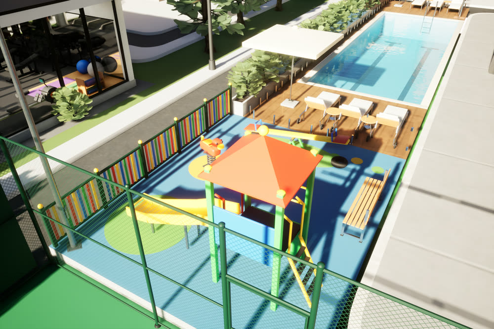 Kids' play area with a slide tower and soft coloured flooring, fenced, next to the pool deck.