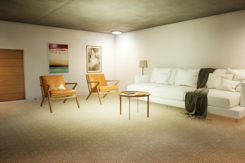 Another view of the living room: the white sofa with a throw, a table lamp, two leather armchairs and framed art on the wall.