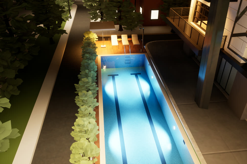 The same lap pool at night, lit from underwater, with warm light on the timber deck.